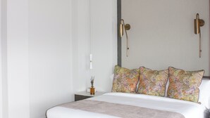 A modern bedroom with a large bed, a chandelier, and wall-mounted lamps.