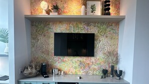 A modern kitchen with a built-in TV, light blue cabinets, and a decorative backsplash.