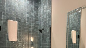 Un baño moderno con ducha envuelta en vidrio, tocador con lavamanos y espejo.