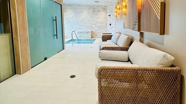 Un interior moderno con zona de piscina, mobiliario de mimbre y pared de piedra.