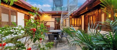 A traditional Japanese-style courtyard with a dining area, a staircase, and a view of a pagoda.