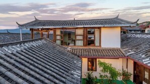 A traditional building with a tiled roof and a wooden structure with windows. - GuanGuanJuJiu Inn (Lijiang)