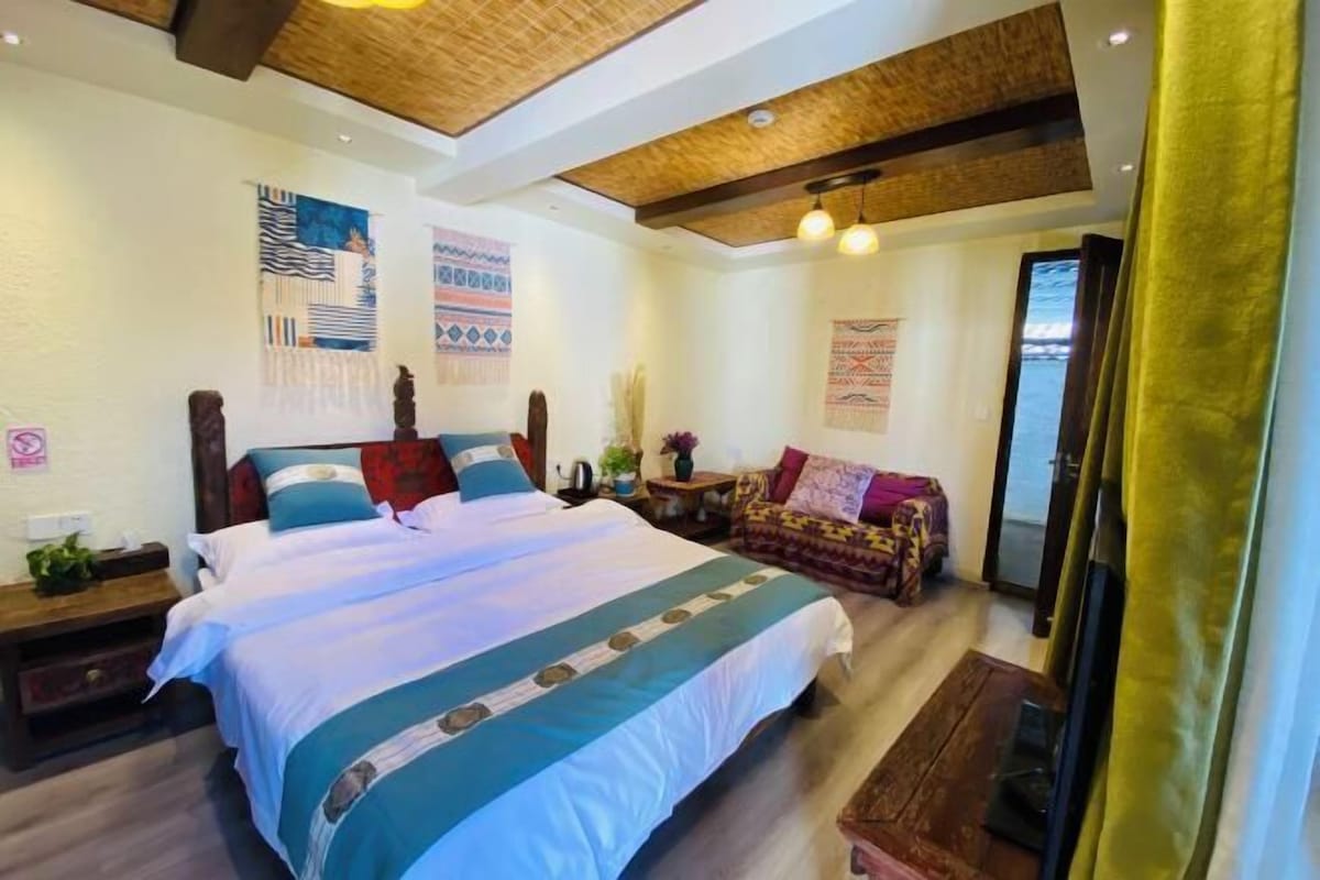 A bedroom with a large bed, wooden headboard, and a ceiling with exposed beams.