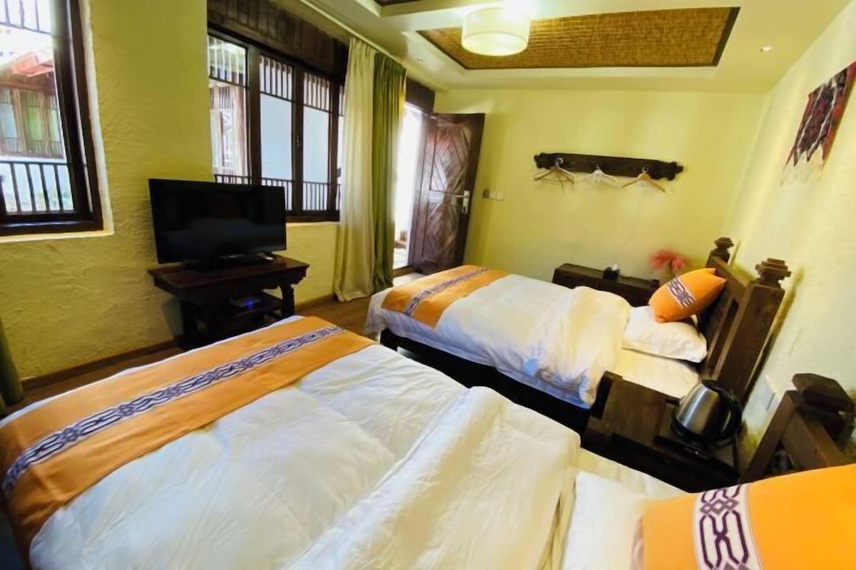 A hotel room with two beds, a television, and a window with bars.