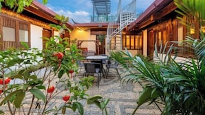 A courtyard with a staircase, outdoor seating, and lush greenery. - GuanGuanJuJiu Inn (Lijiang)
