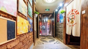 A hallway with a patterned carpet, wooden walls, and artwork. - GuanGuanJuJiu Inn (Lijiang)