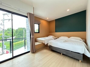 A hotel room with two beds, a large window, and a view of greenery.