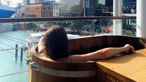 Una persona relajándose en una bañera de madera con vistas a la ciudad.