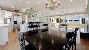 A spacious kitchen with white cabinets, a large island, and a view of the sea.