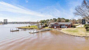 A waterfront property with a dock, a house, and a clear view of the water.