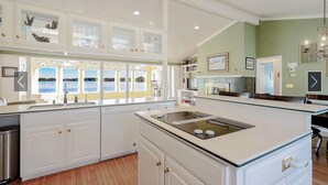 A modern kitchen with white cabinetry, a built-in stove, and a view of the outdoors through large windows.