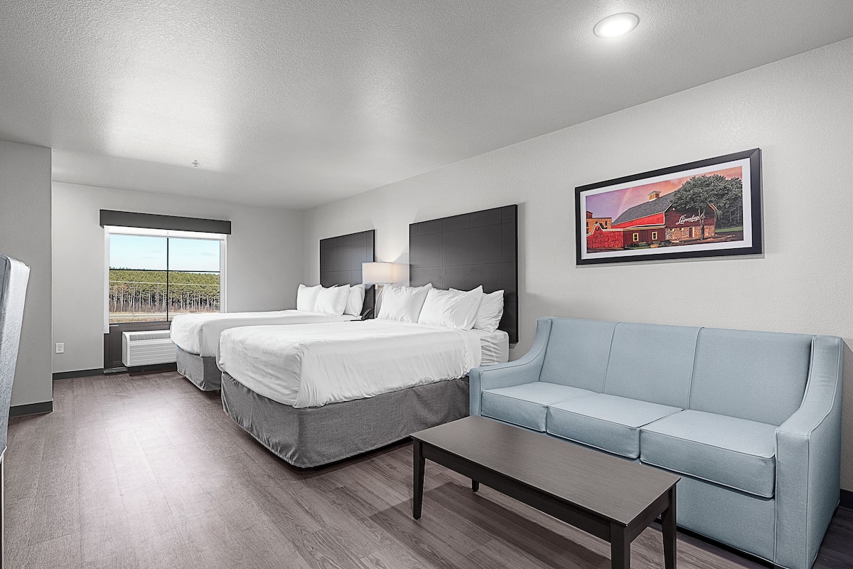 A hotel room with a bed, a sofa, a desk, and a window with a view.