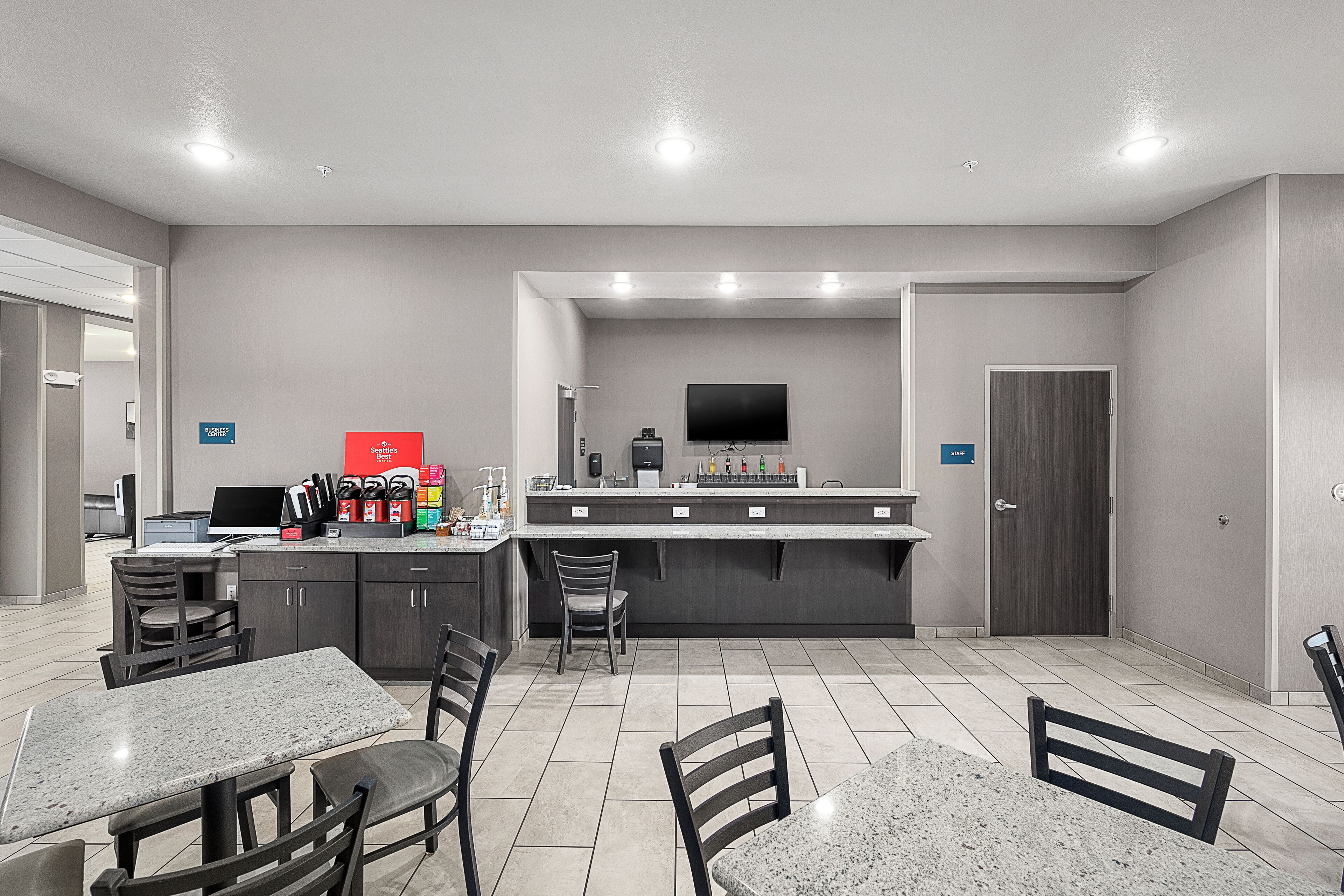 A modern kitchen area with a bar counter, seating, and a flat-screen TV mounted above the counter.