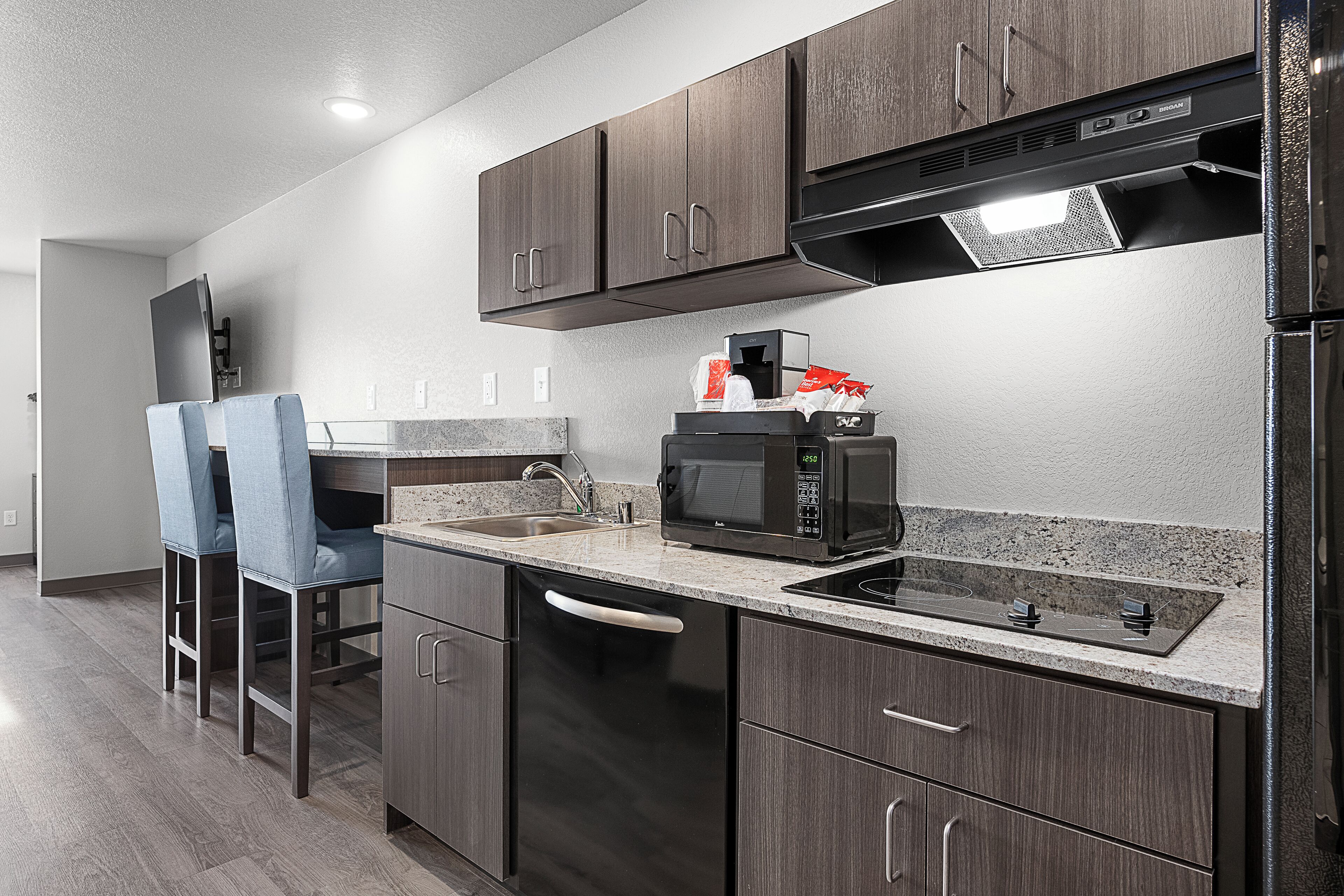 Una cocina moderna con alacenas de madera oscura, un refrigerador de acero inoxidable, un microondas y un lavavajillas.