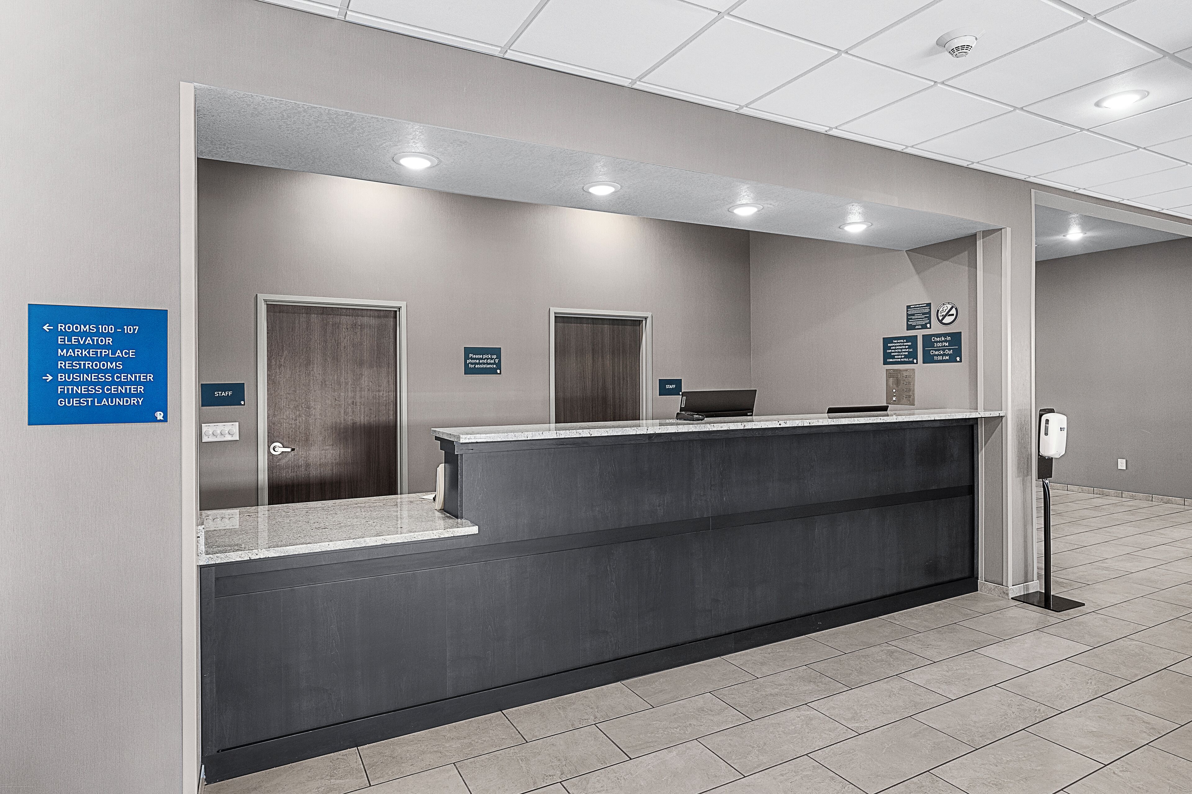 A reception area with a counter, a sign indicating the location of the elevator, and a sign for the business center.