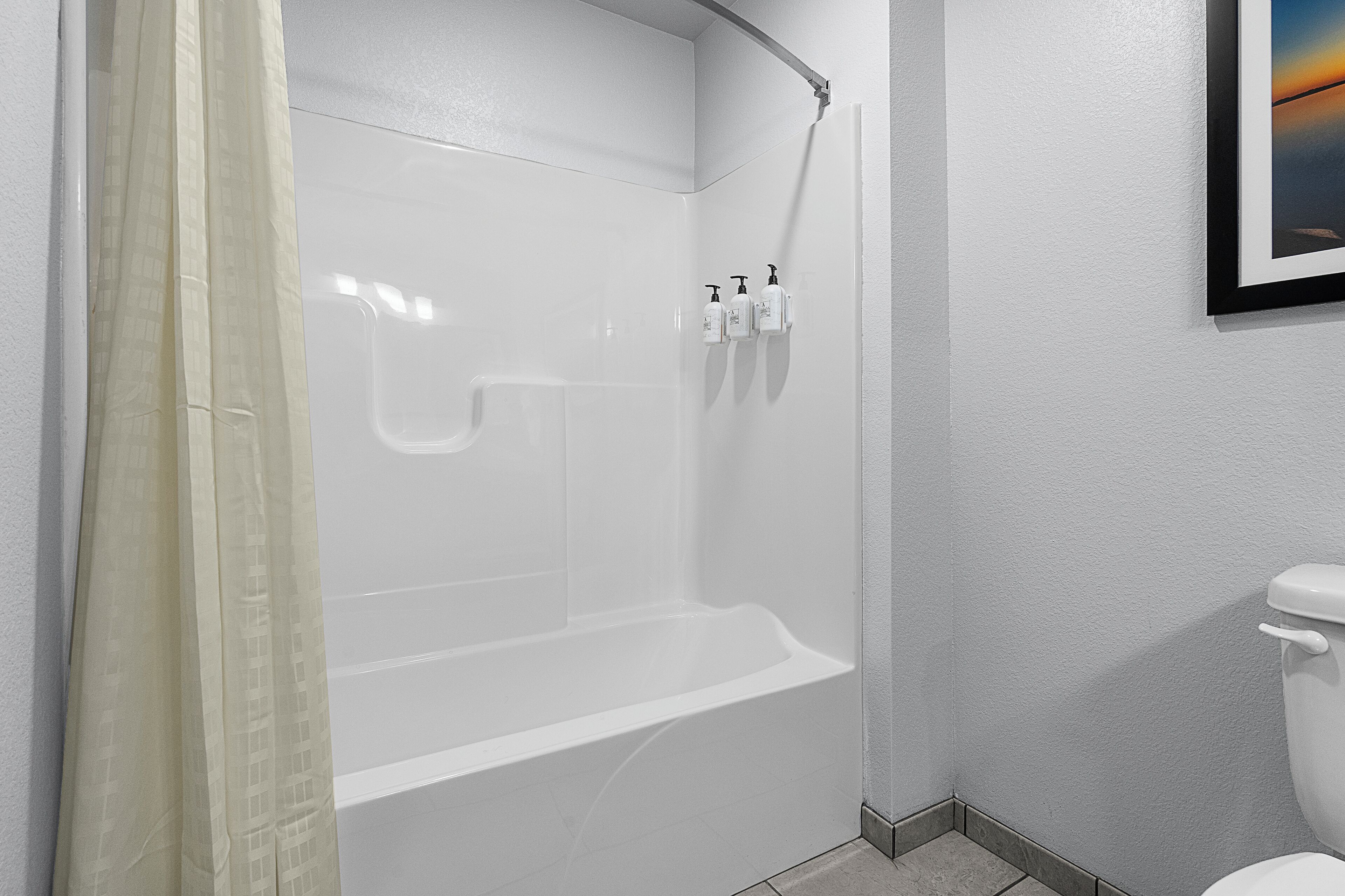 Un baño moderno con ducha a ras de suelo, inodoro y un cuadro enmarcado en la pared.