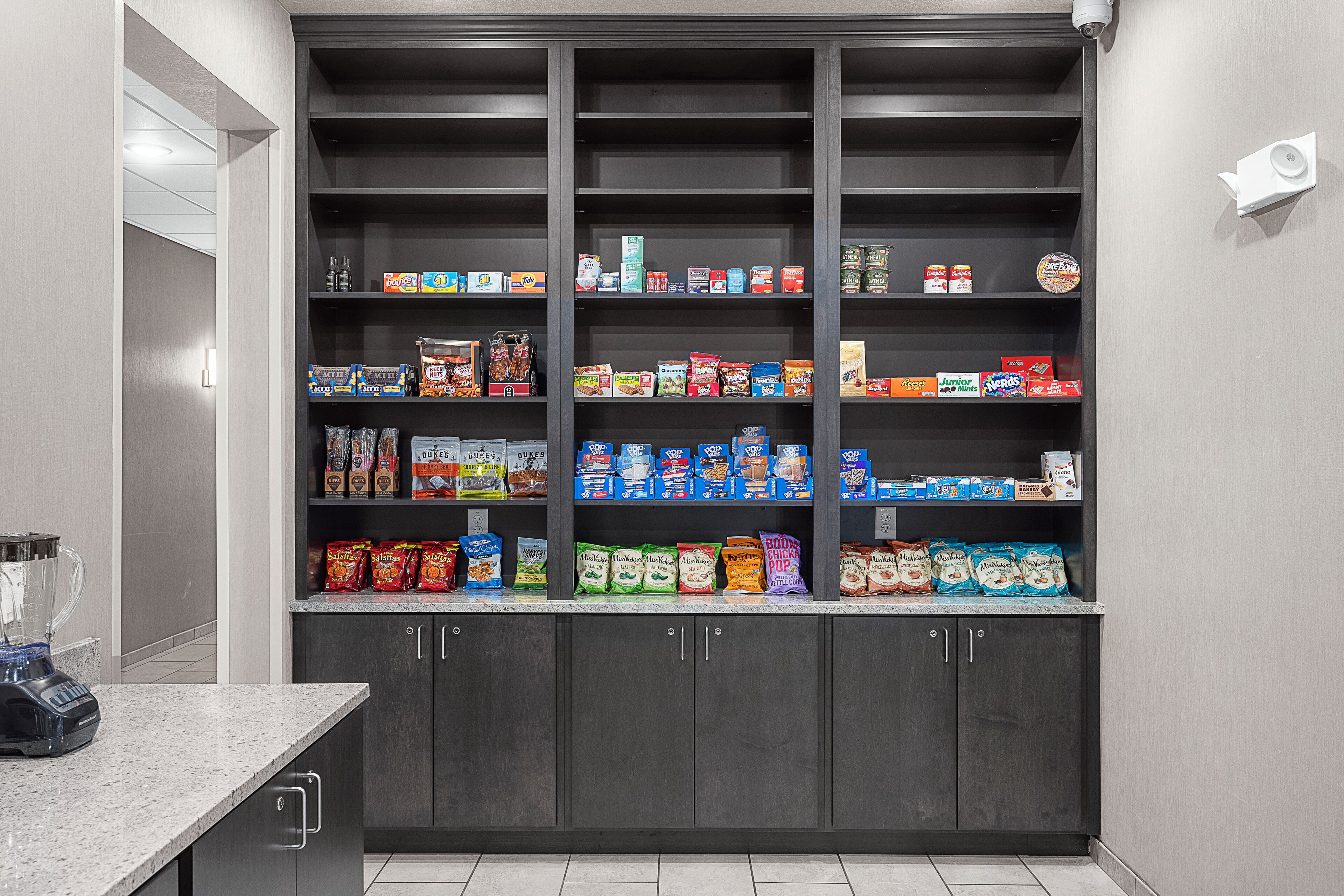 A pantry stocked with various food items and a blender on the counter.