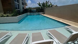 A swimming pool with lounge chairs and a view of a building. - THE Aracari (Noord)