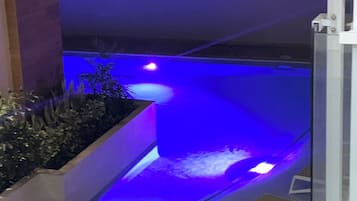 Una piscina al aire libre, sombrillas, sillones reclinables de piscina