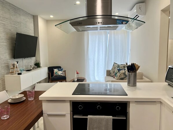 Una cocina moderna con una isla central, horno empotrado y una campana extractora grande.