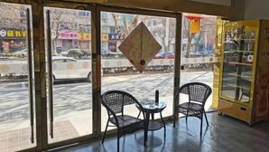 Una habitación con dos sillones negros de mimbre, una mesita y vista a la calle.