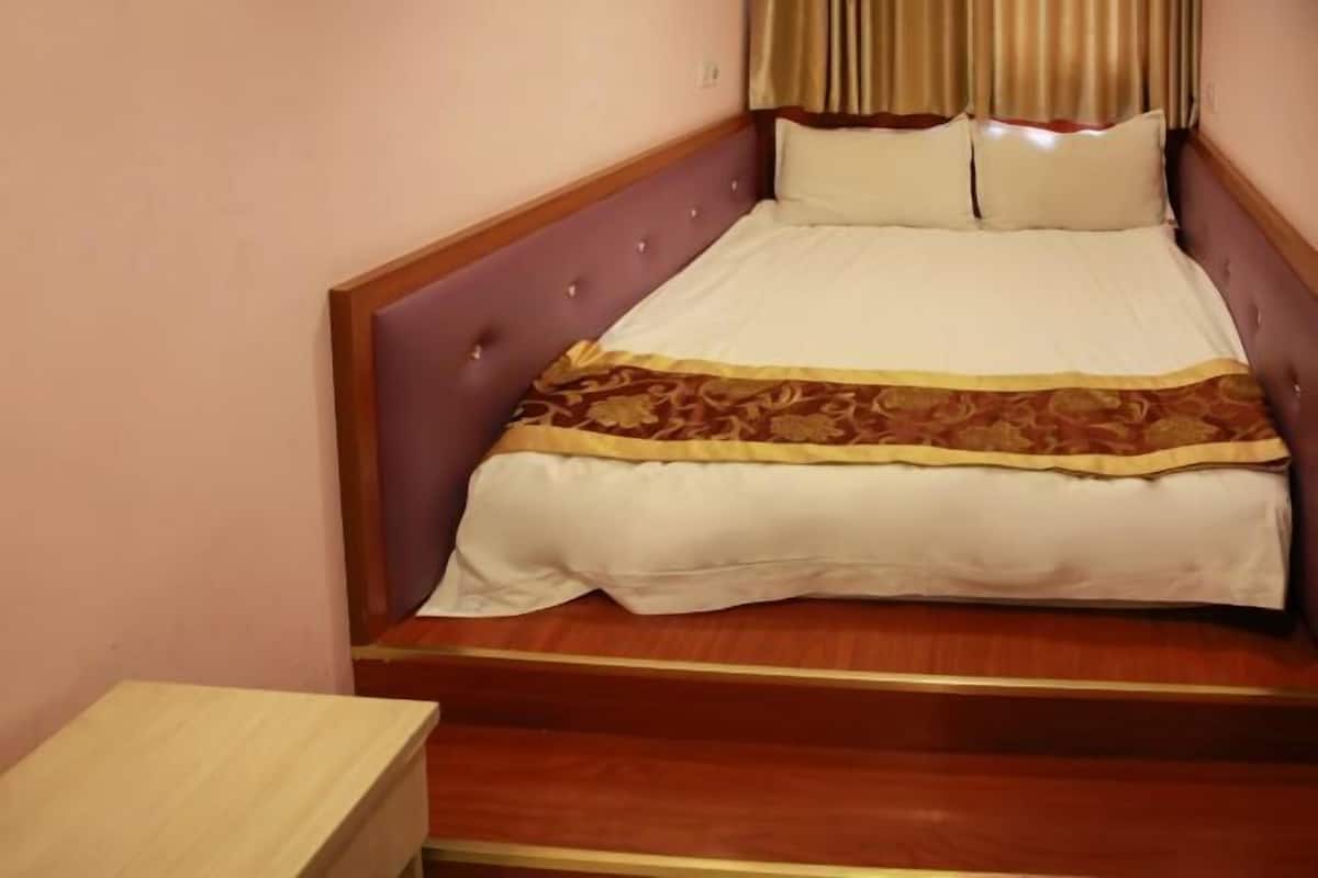 A single bed with a headboard, a wooden nightstand, and a patterned bedspread.