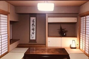 Perinteinen japanilainen huone, jossa on tatamimatto, matala puupöytä, seinälle ripustettu taulurulla ja lyhty.