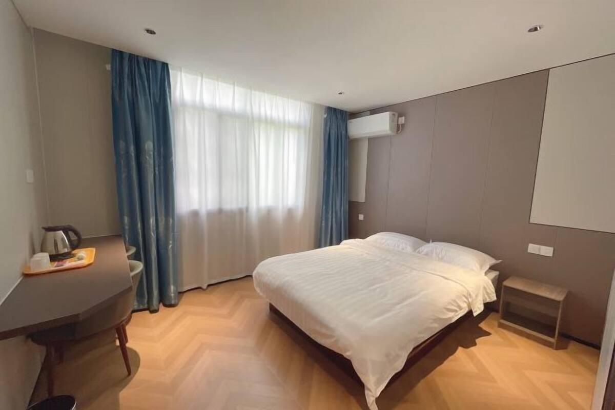Una habitación de hotel con cama, escritorio con tetera, silla y una mesita.