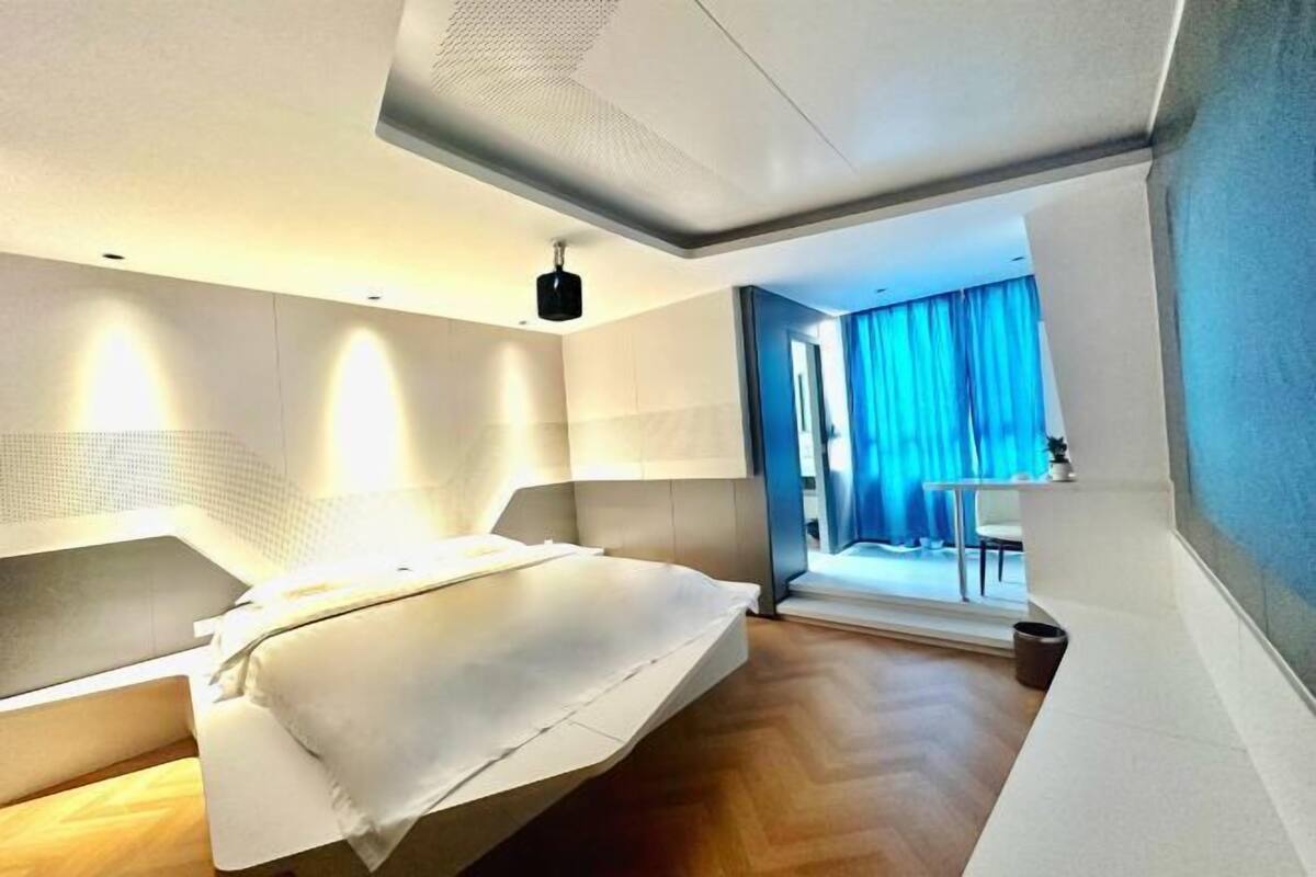 Un dormitorio moderno con cama, estanterías empotradas y vistas a un balcón.