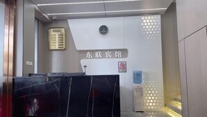 A reception desk with a black marble top, a clock above it, and a sign that reads "East Lobby". - Nanning Donglian Hotel (Guangxi Police School Xianhe Campus Shop) (Nanning)