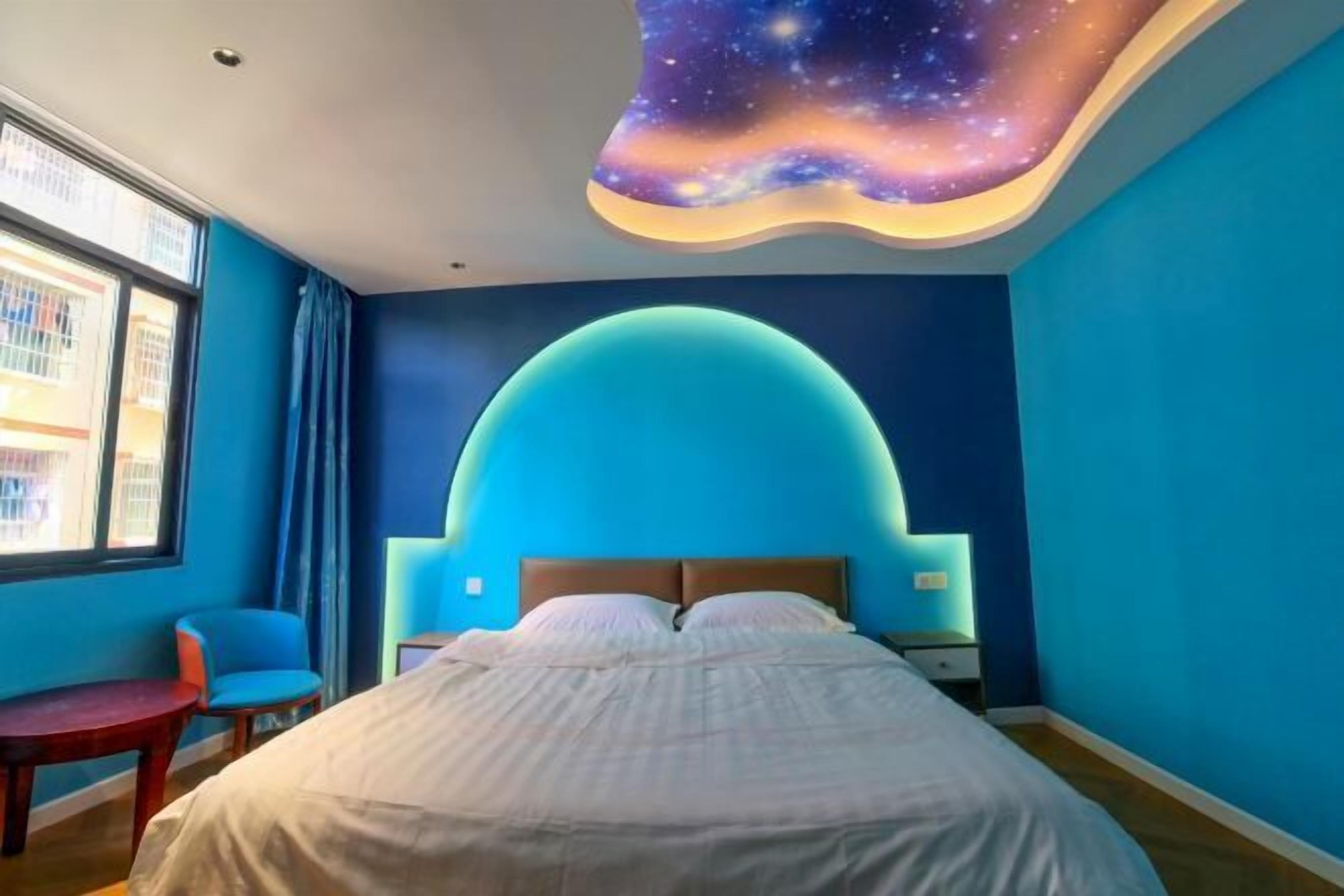 A bedroom with a curved ceiling, a bed, a nightstand, a chair, and a window with curtains.
