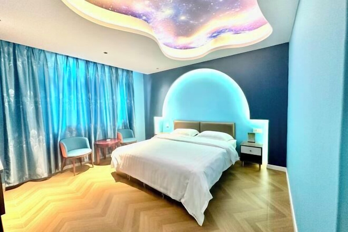 Un dormitorio moderno con un diseño de techo curvo, una cama grande, una mesita de noche y una silla.