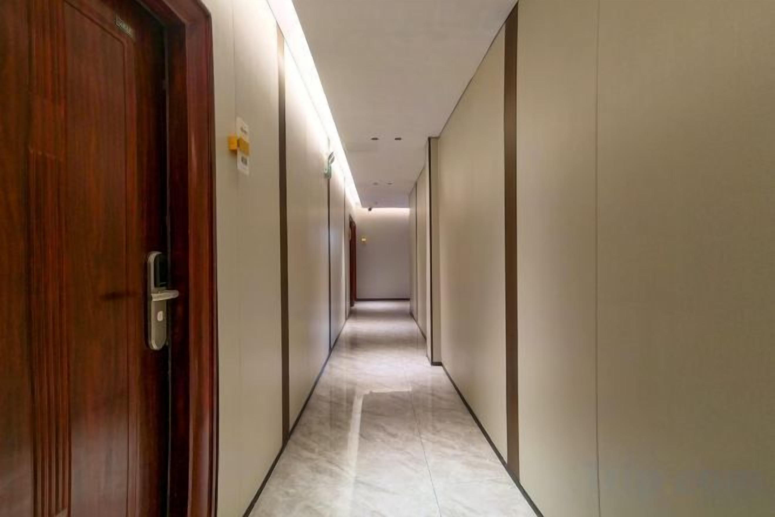 A hotel corridor with doors on both sides, a marble floor, and a ceiling with recessed lighting.