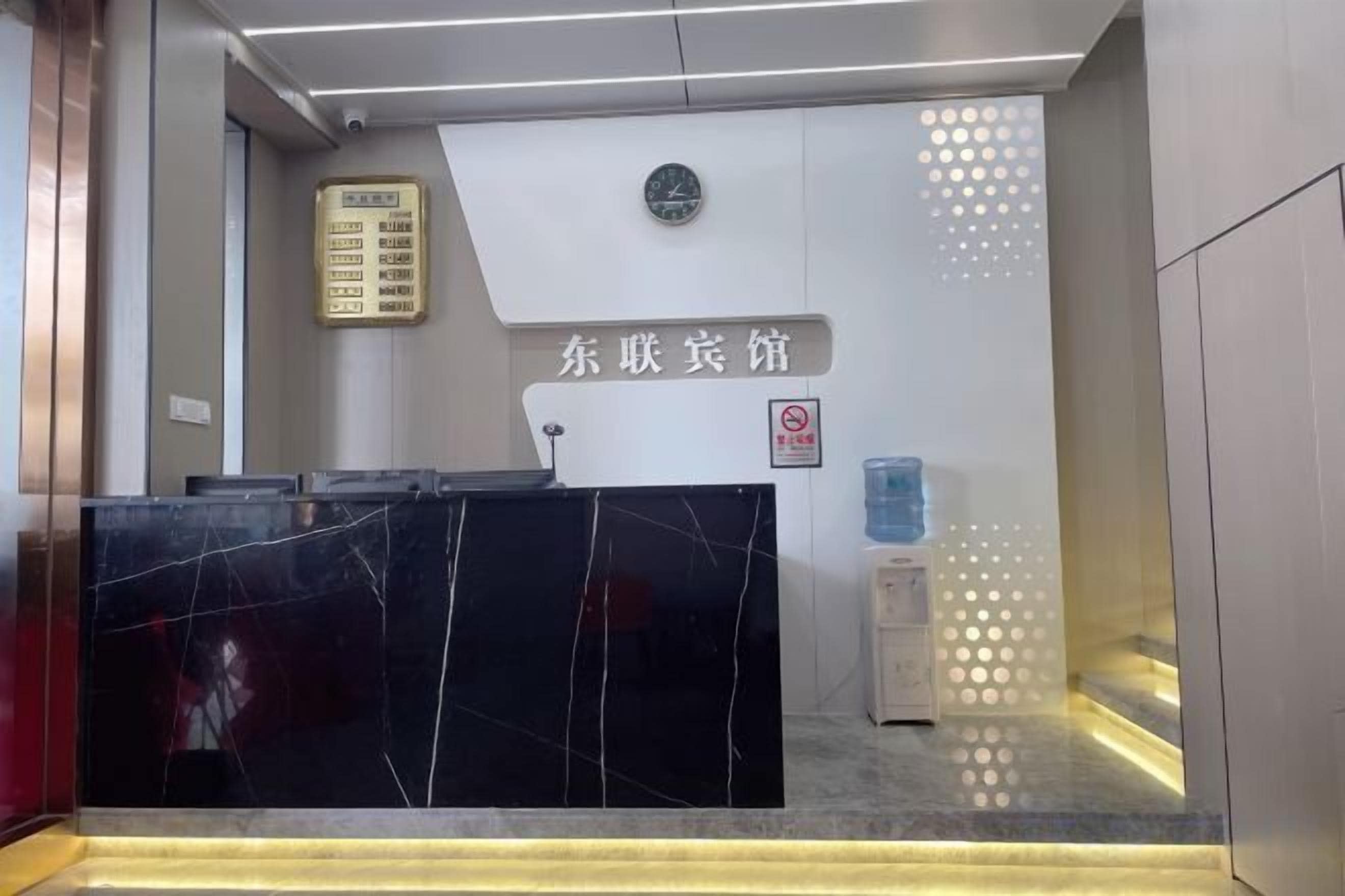 A reception desk with a black marble top, a clock, and a sign with Chinese characters.