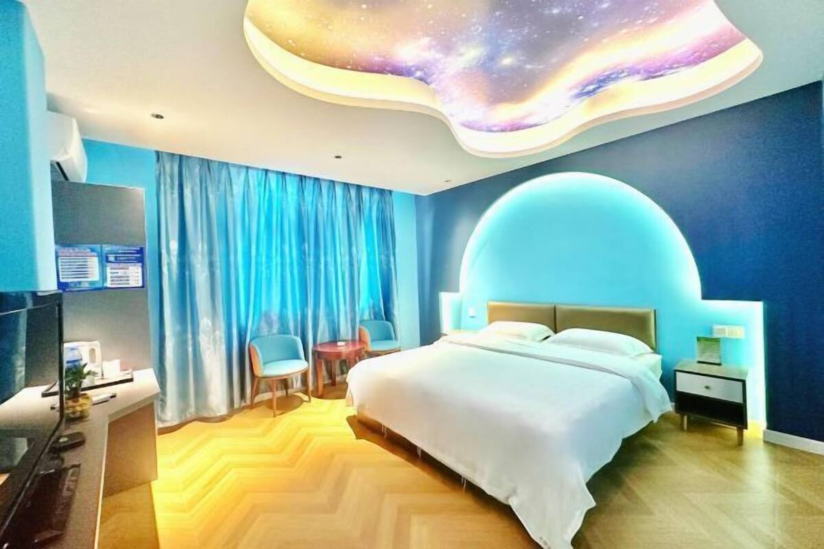 Habitación de hotel moderna con techo curvo, cama, escritorio y televisor.