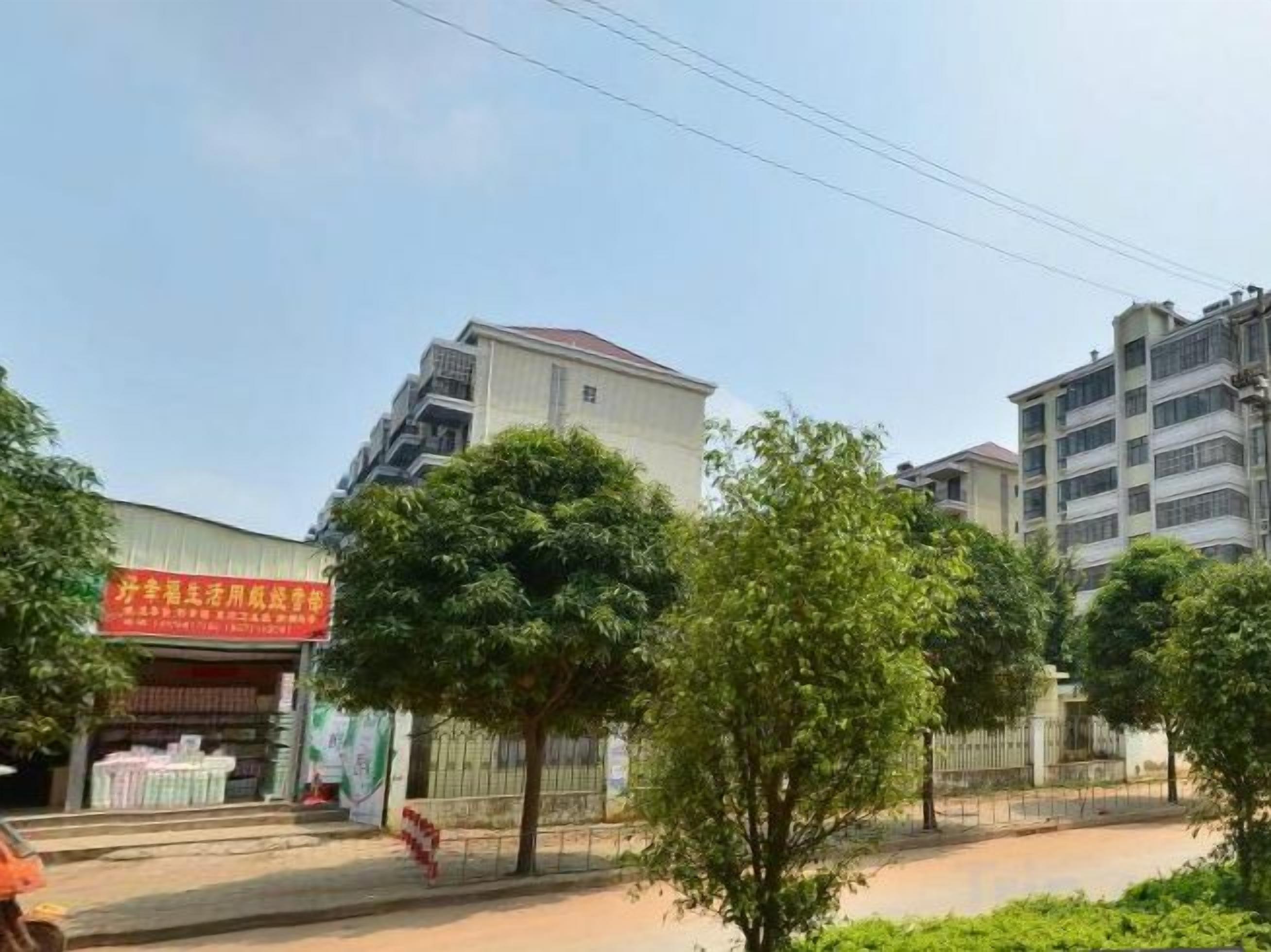 A multi-story building with a flat roof and a signboard on the ground level.