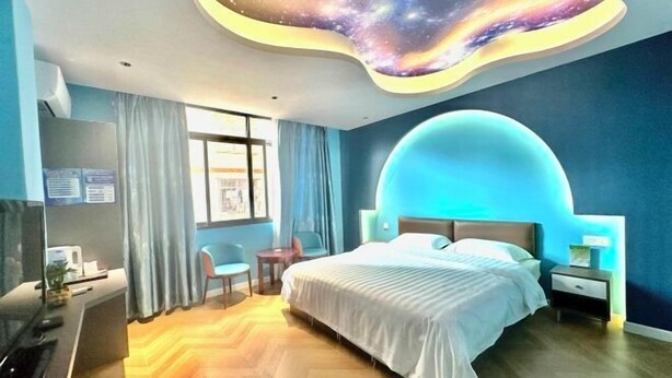 A modern hotel room with a curved ceiling, a large bed, a desk with a computer, and a window with curtains. - Nanning Donglian Hotel (Guangxi Police School Xianhe Campus Shop) (Nanning)