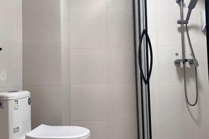 Un baño con inodoro, cabina de ducha y calentador de agua.
