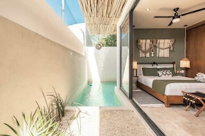 Une chambre à coucher avec un lit, une table de chevet, une lampe et une vue sur une piscine.
