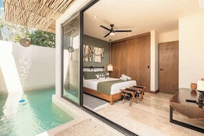 Une chambre avec un lit, un ventilateur de plafond, une table de chevet, une table et une vue sur une piscine extérieure.