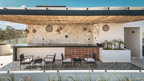 An outdoor patio with a stone wall, a modern bar area, and seating. - Gem in the Jungle Private Pool Beach Club Access (Tulum)