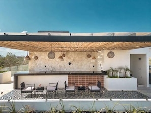 Une terrasse extérieure avec un mur en pierre, un bar moderne et des sièges.