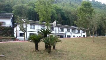 A traditional building with a tiled roof, surrounded by a grassy area with a few trees.