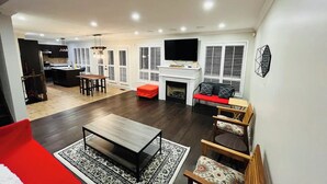 A modern living room with a fireplace, a television, and a dining area. - Spacious & Elegant 3BR + Office (Brantford)