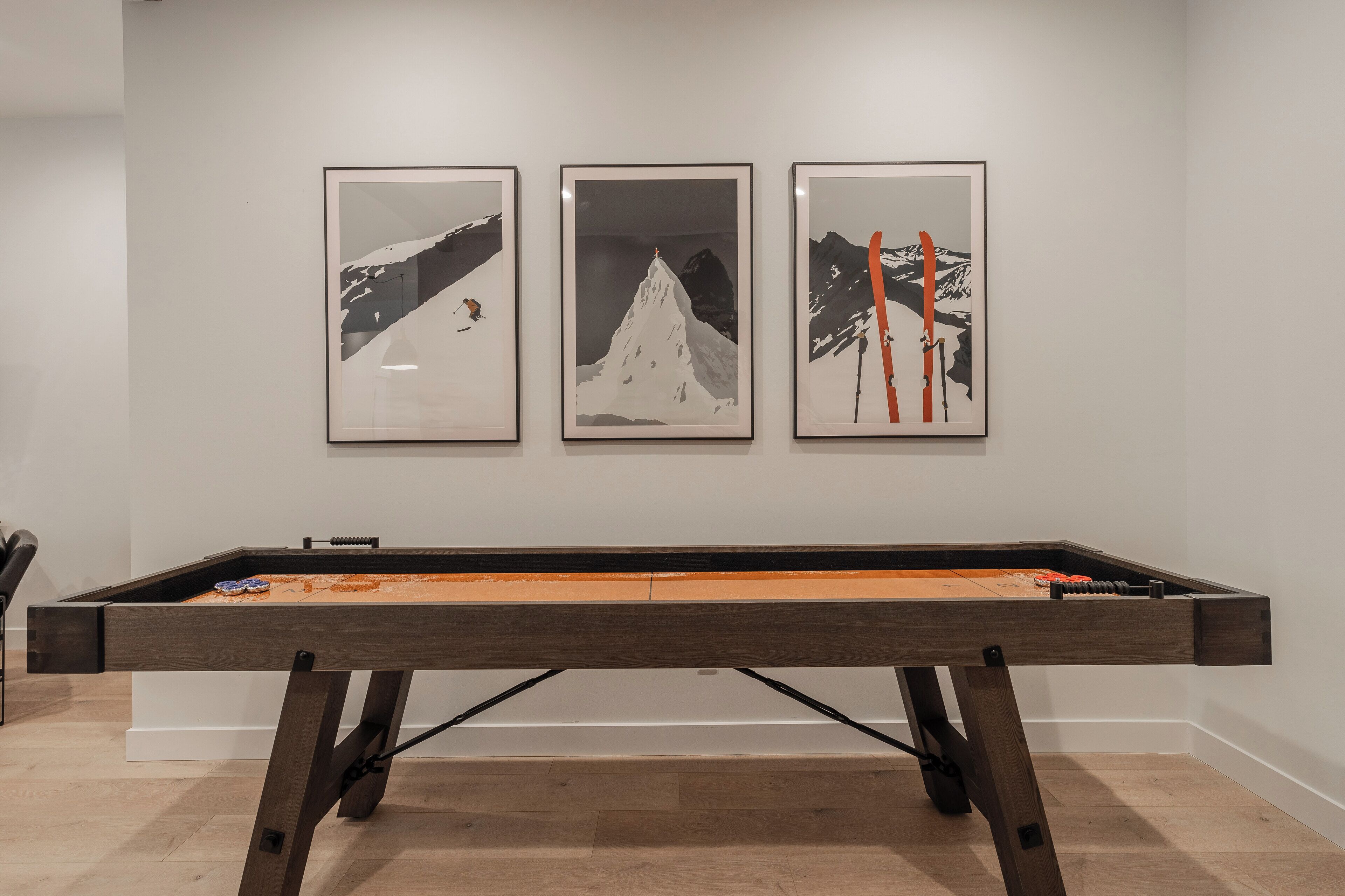 A pool table with three framed artworks on the wall behind it.