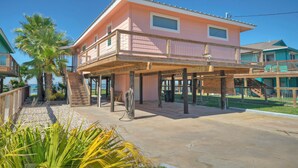 A pink building with a balcony and a staircase leading to the upper floor. - Fish - Relax - Repeat! Waterfront Retreat with Private Pier in Rockport, TX (Rockport)