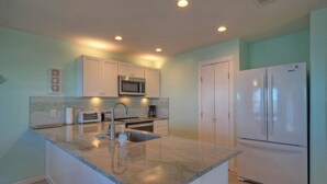 A modern kitchen with a central island, stainless steel appliances, and light teal walls. - Fish - Relax - Repeat! Waterfront Retreat with Private Pier in Rockport, TX (Rockport)