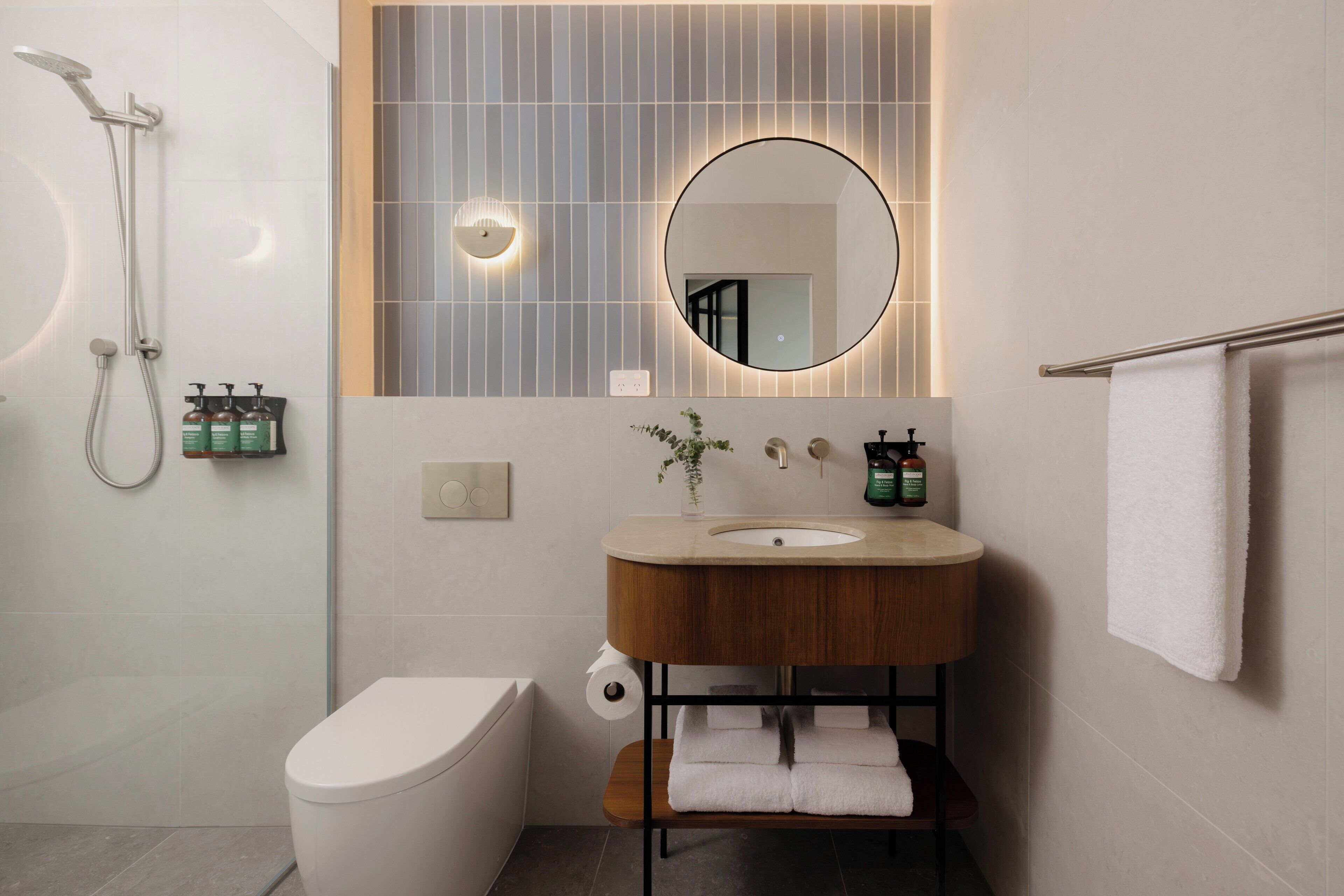 Un baño moderno con inodoro, lavamanos y ducha.