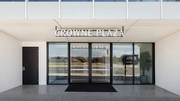 The entrance to Crowne Plaza with a glass door and a black mat in front.