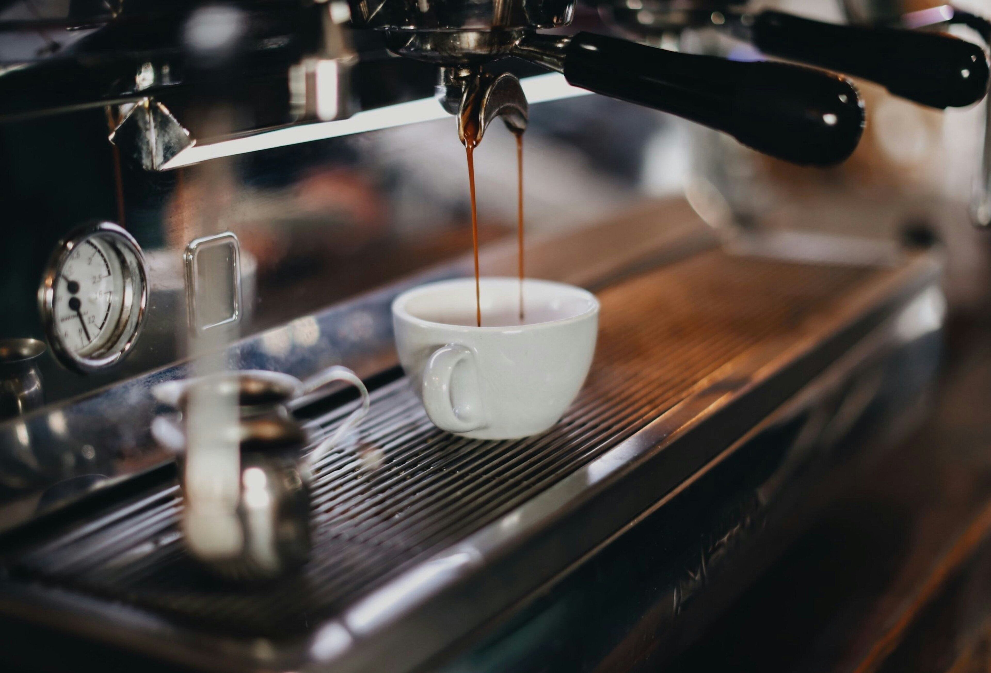 Een koffieapparaat schenkt espresso in een kopje.